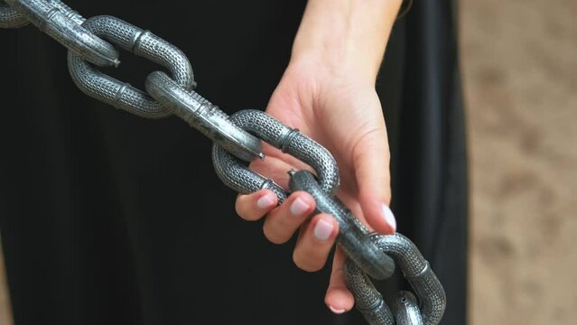 Close up portrait fantasy goth woman holding pulling iron chains shackles in hands. Girl witch princess fashion model in long black dress. Cropped face part of body. Concept slavery captive prisoner