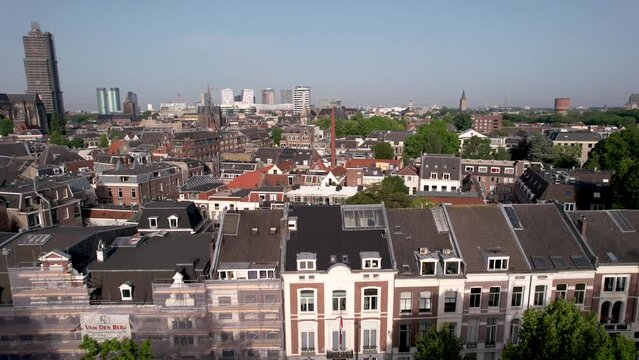Aerial reveal of De Dom medieval cathedral tower in scaffolding in Dutch city center of Utrecht towering over the cityscape during sunrise