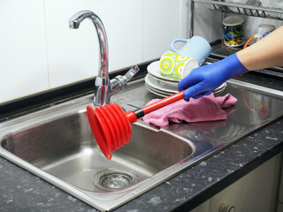 Stainless steel sink, tap water, red plunger. Pipe obstruction