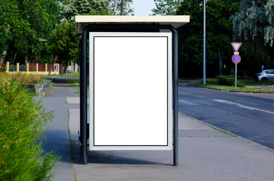 Bus Shelter At A Busstop. Blank Billboard Ad Display. Empty White Lightbox Sign. Glass And Aluminum Frame Structure. City Transit Station. Bench Inside. Urban Street Setting. Outdoor Advertising