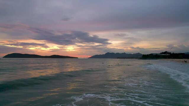 Surfers waiting to catch a wave during sunset at Pentai Tengah Beach, Malaysia