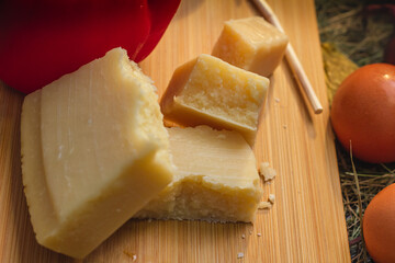 still life with vegetables and cheese on a cutting board in the hay