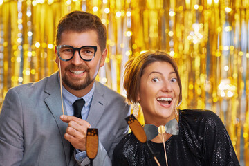 Couple over gold with photo booth accessories on party