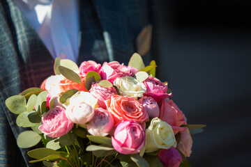 The groom holds in his hands a wedding bouquet of white and pink rose flowers. The concept of a holiday, wedding.