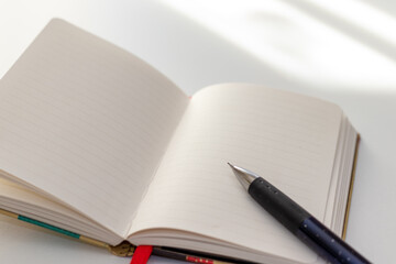 窓際の机に置かれたノートとペン