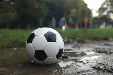 Fototapeta na wymiar Dirty leather soccer ball in puddle outdoors