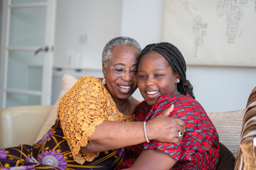 Smiling senior woman hugging teenage granddaughter at home