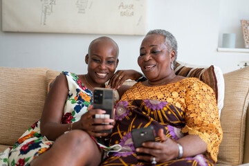 Smiling woman with mother having video call on smart phone at home