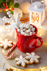 Obraz na płótnie Canvas Hot chocolate with marshmallows in red mug in Christmas decoration with bokeh lights.