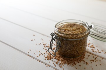 Jar of whole grain mustard on white wooden table. Space for text