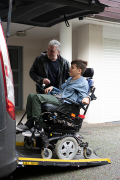 Father and disabled son using wheelchair lift 