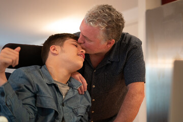 Father kissing disabled son on forehead