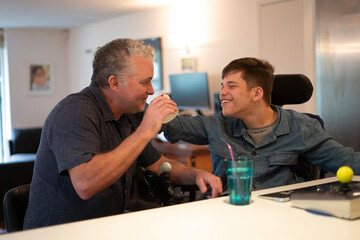 Father and disabled son laughing at home