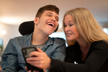Mother using smartphone with disabled son