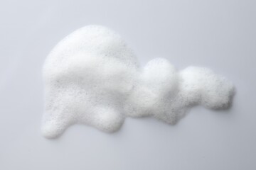 Drop of fluffy soap foam on white background, top view