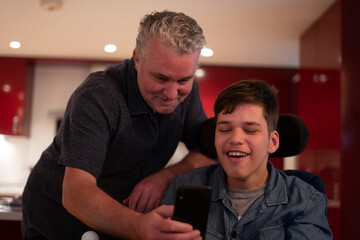 Father using smartphone with disabled son at home