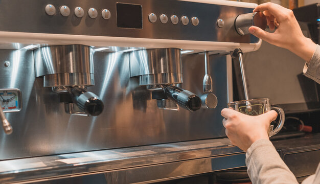 Detalle de camarero irreconocible, preparando t&eacute;, en la cafetera del bar.