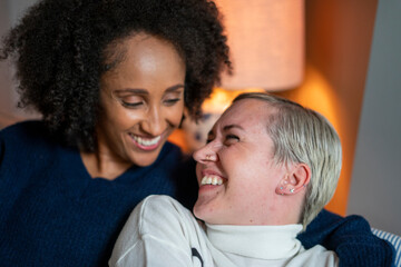 Close-up of smiling lesbian couple embracing at home