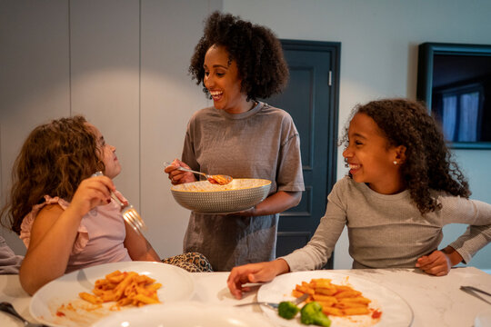 Mother with two daughters enjoying dinner in kitchen
