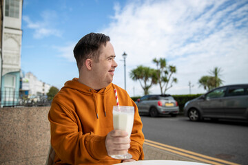 Man drinking milkshake in sidewalk cafe