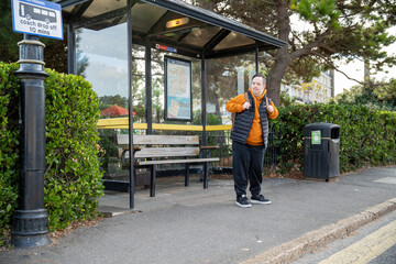 Man waiting at bus stop - obrazy, fototapety, plakaty