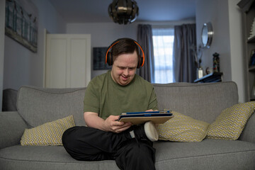 Fototapeta Man sitting on sofa and using digital tablet obraz