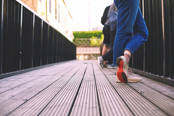 Women's legs in jeans and sneakers stand on a wooden bridge. Place for text and design