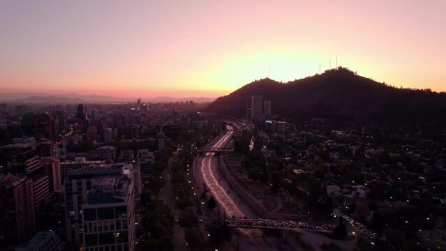 Traffic On Father Letelier Bridge Spanning The Mapocho River Next To Sculpture Park With Parquemet Santiago Metropolitan Park At Dusk In Chile. - aerial