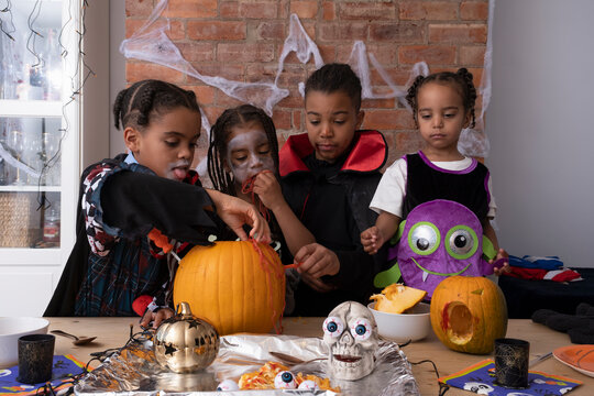 Children in Halloween costumes making Jack OLantern