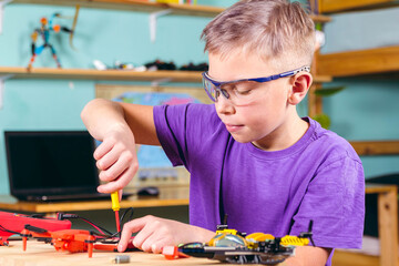The boy is fixing the drone. Primary technical education.