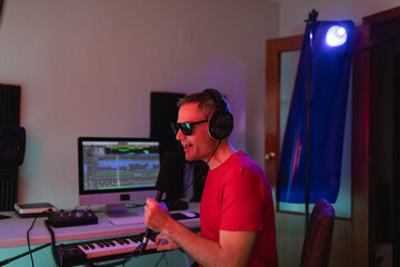 Music producer singing in order to place some vocal layers for a project during a recording session at his home studio