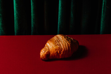 A golden fresh and soft croissant on a Christmas background with room for text. Creative design of festive pastries for Christmas. A stylish concept of advertising desserts and food delivery.