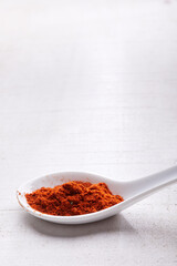 Paprika in a white spoon on white wood