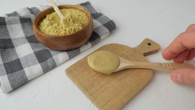 Mustard powder in wooden bowl. Mustards are plants of the genera Brassica and Sinapis.