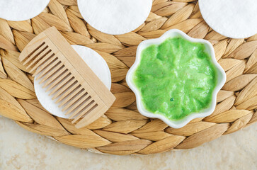 Homemade matcha green tea (kelp, algae, spirulina) hair, face or eye mask in a small white bowl and wooden hairbrush (comb). Natural beauty treatment and spa recipe. Top view.
