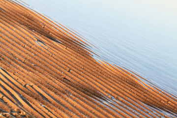Sea water and golden sand closeup. Selective focus