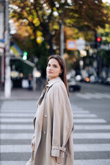 Young woman walks on street against background of crosswalk and traffic light.