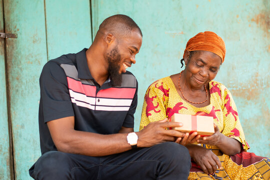 Young Black Man Gives An Old Black Woman A Present