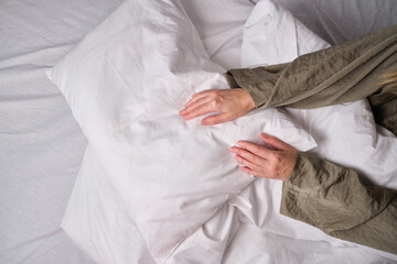 Woman making the bed. Pillow from sheets close-up. Get up. Dream. Good morning in the bedroom. Cozy and comfortable. Wellness, relaxation, lifestyle
