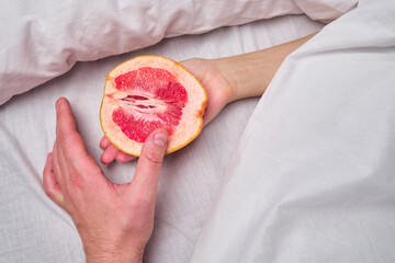 Woman is holding a grapefruit in bed. Female masturbation concept sexy fruit composition. Juicy...