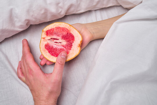 Woman is holding a grapefruit in bed. Female masturbation concept sexy fruit composition. Juicy fruit and vagina symbol