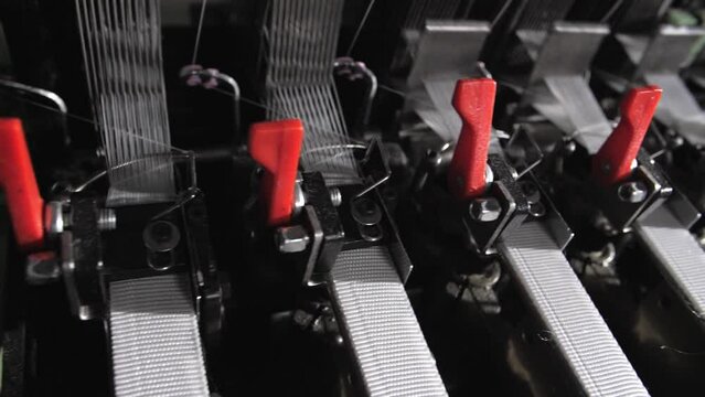 Close up of textile machine in slow motion. Fibre thread lines on the weaving loom machine. A loom machine for clothing or woven clothes. Weaving machine for garment industry.