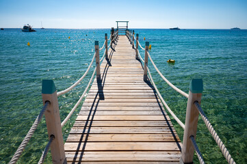 Naklejka premium Wooden pier for guests of yachts on legendary Pampelonne beach near Saint-Tropez, summer vacation on white sandy beaches of French Riviera, France