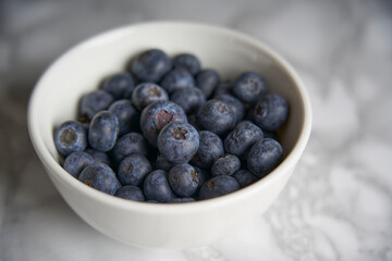 A group of fresh blueberries on a white and black marble table. 