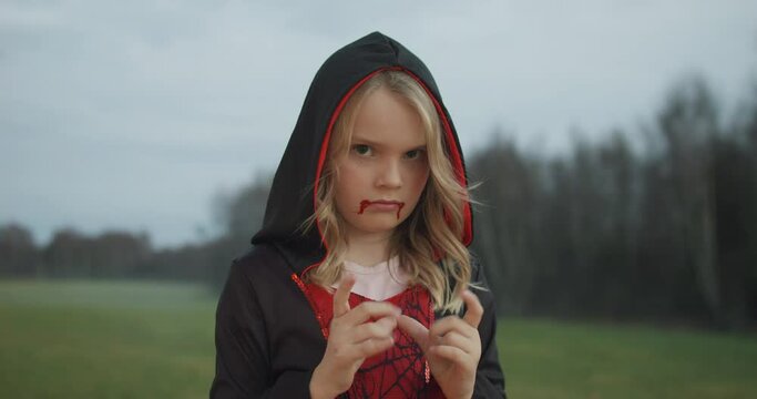 Portrait of small blonde girl in vampire costume, static view