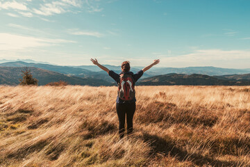 Girl with a backpack and outstretched arms enjoys the autumn mood view of the mountains - 544871785