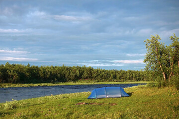 Large blue tent  by the river on sunny day in Swedish Lapland at end of July 2022.