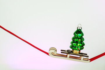 Minimalistic Christmas card. Christmas tree toy glass green Christmas tree on a red ribbon. Happy New Year 2023. Merry Christmas greetings.