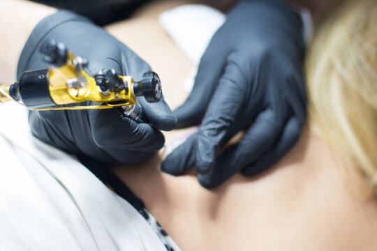 Manos de un tatuador tatuando a una mujer.