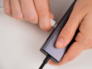 A woman inserts a white Type C cable into a black port.